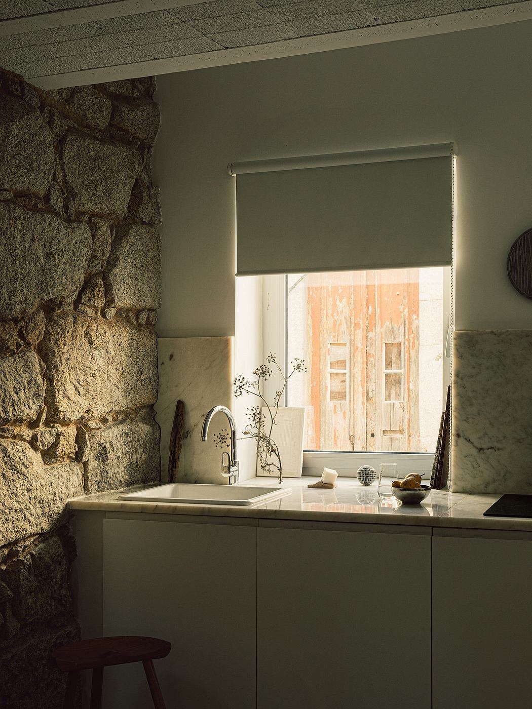 A cozy kitchen with a stone wall, wooden accents, and a minimalist sink design.