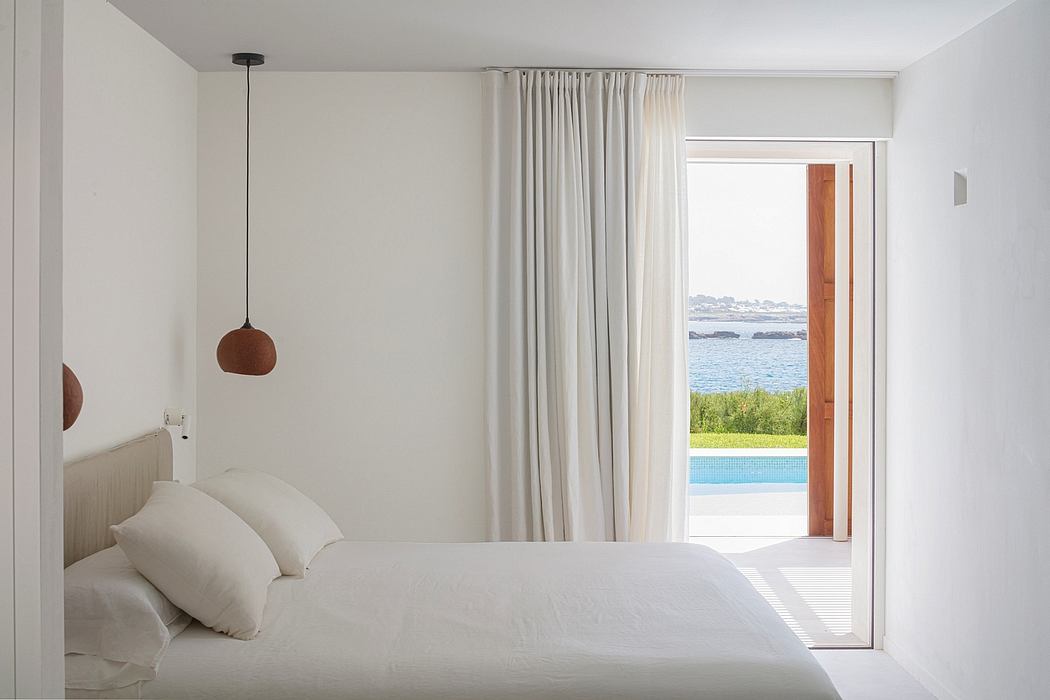 Minimalist bedroom with modern pendant light, floor-to-ceiling windows, and a view of the pool and ocean.
