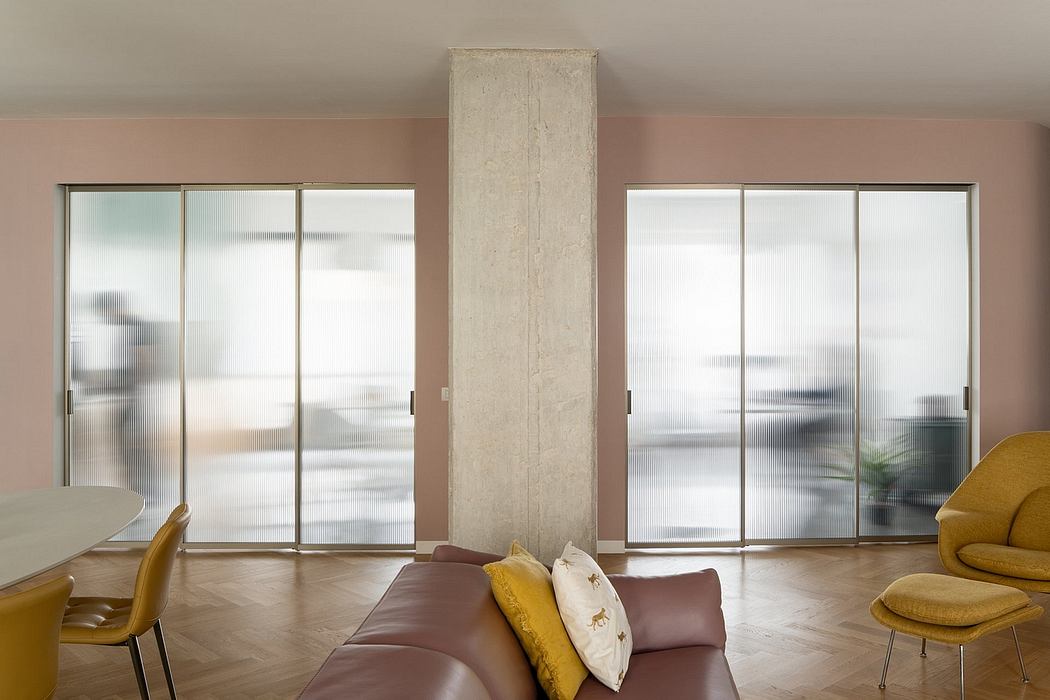 Spacious modern interior with large sliding glass doors, textured concrete column, and cozy seating.