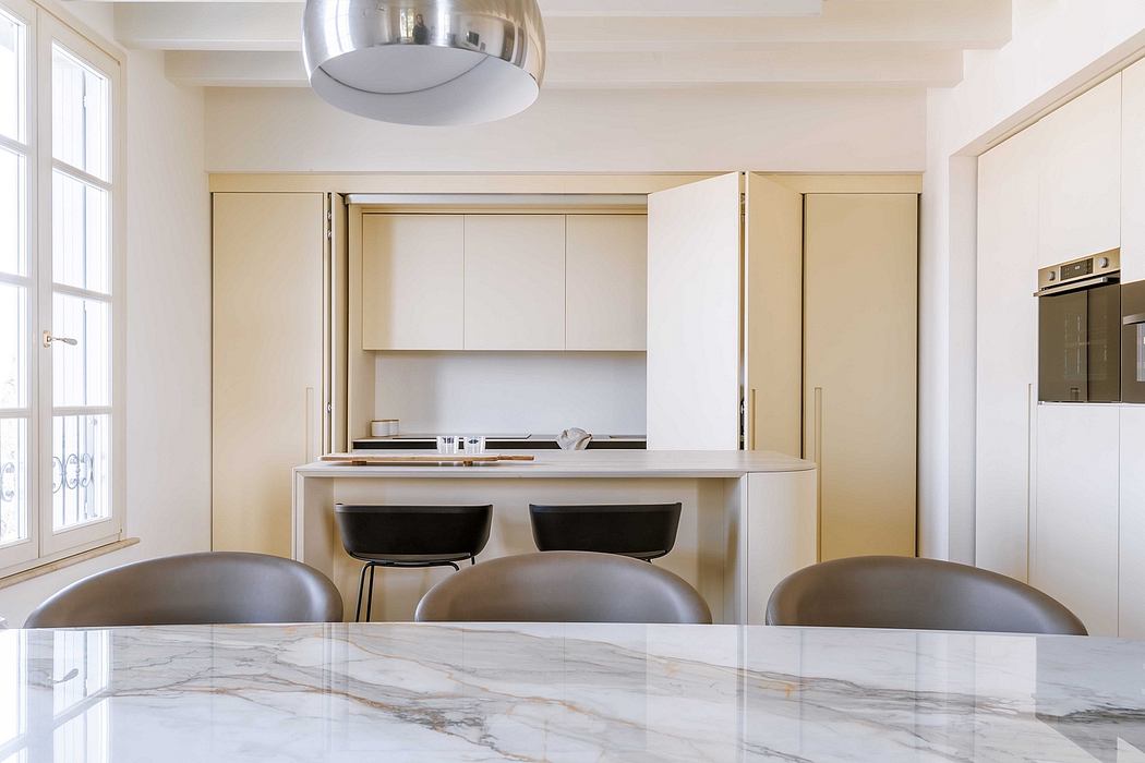 Modern kitchen with sleek white cabinetry, marble countertops, and recessed lighting.