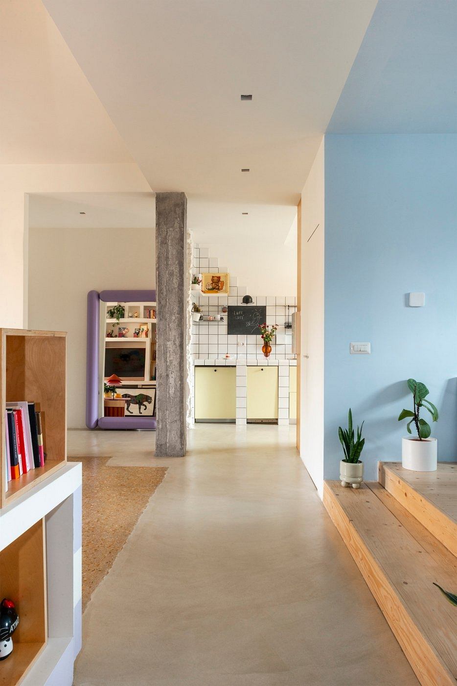 Open floor plan with concrete column, tiled kitchen, wood furniture, and indoor greenery.