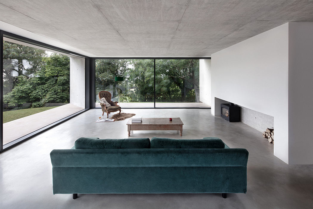 Minimalist living room with large windows overlooking lush greenery, concrete ceiling, and velvet sofa.