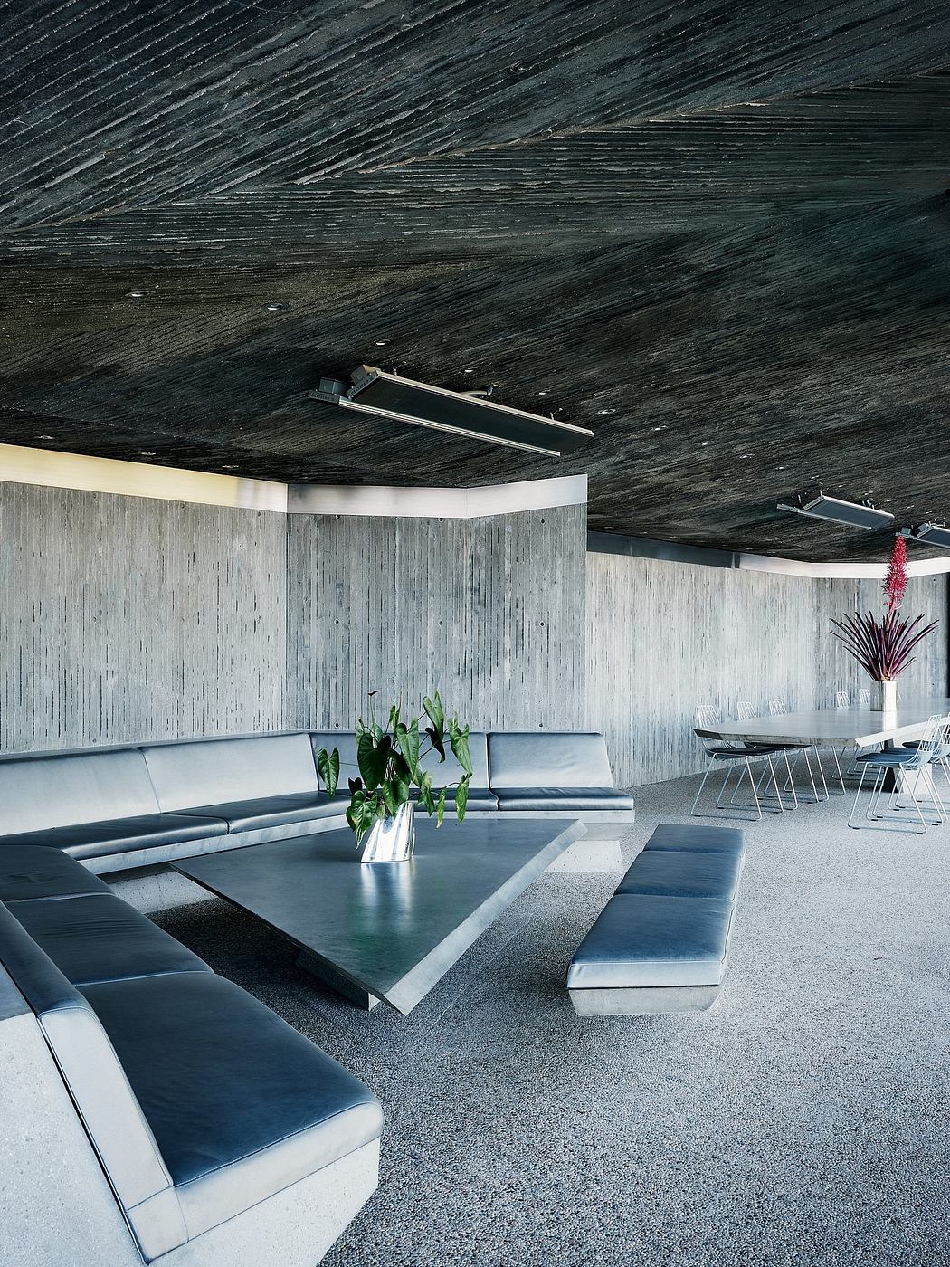 Modern, sleek interior with dark wood panels, curved sofas, and a low glass-topped table.