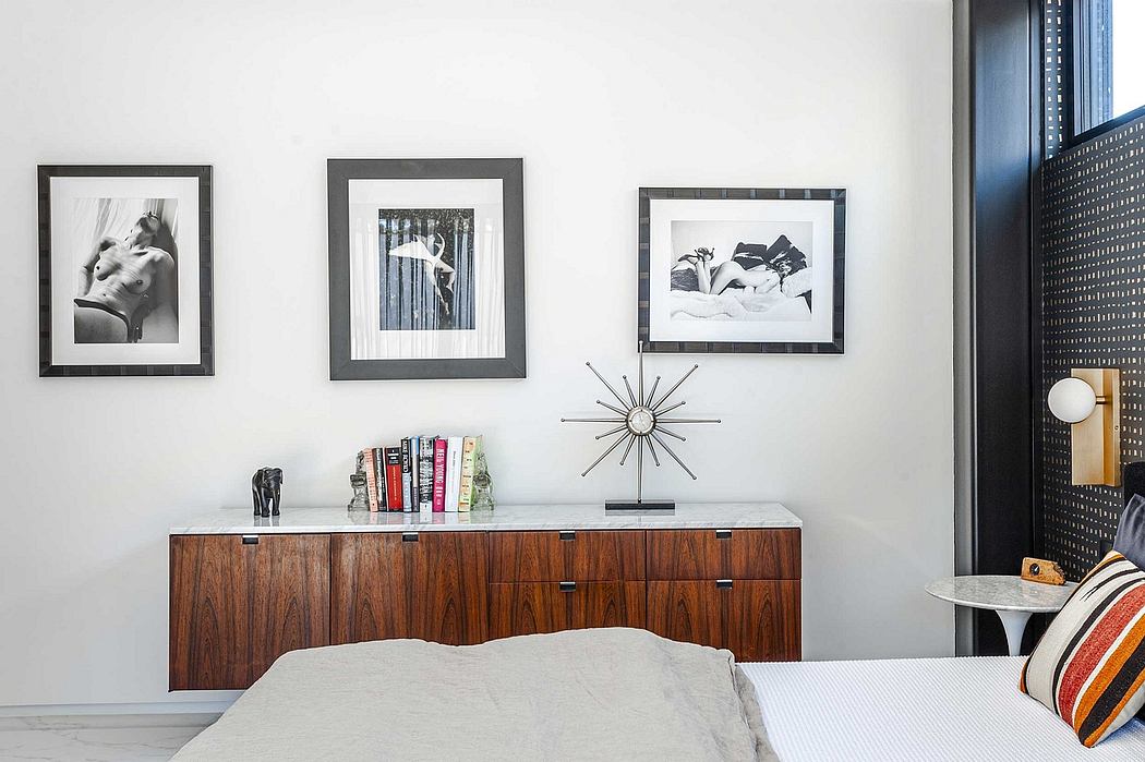 A modern bedroom with sleek wooden furniture, framed artwork, and an ornate starburst clock.