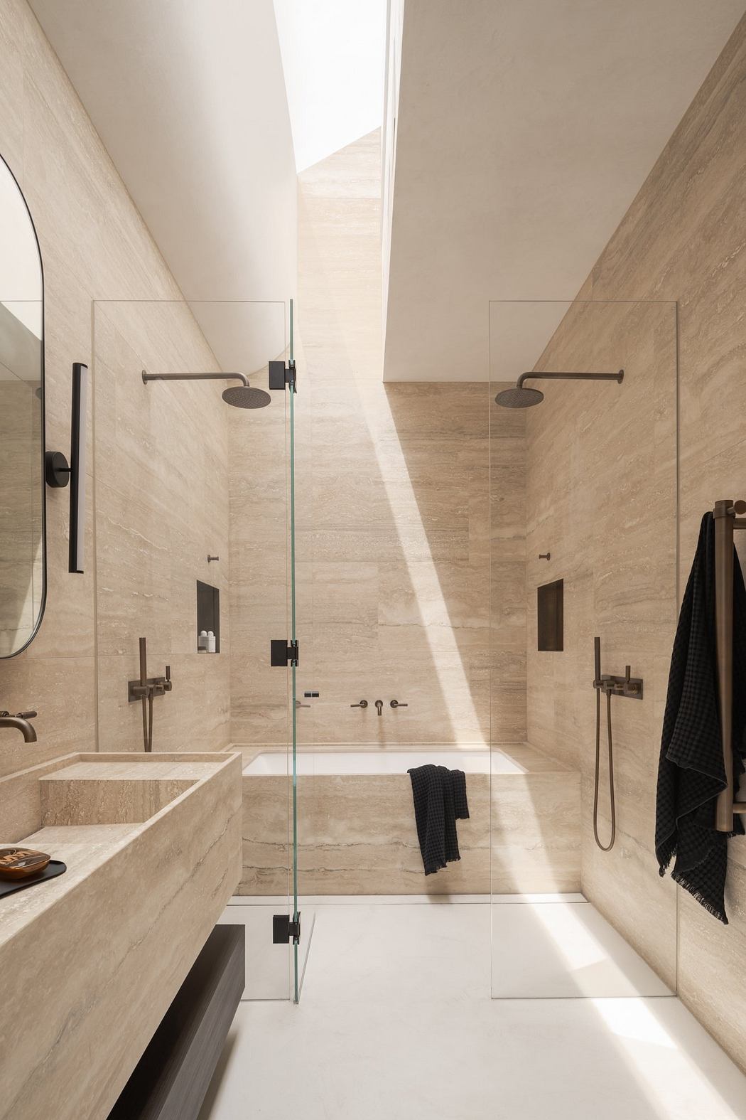 A modern, minimalist bathroom with glass walls, natural stone tiles, and sleek fixtures.