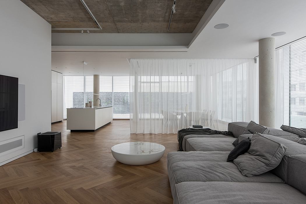 Minimalist living room with concrete ceiling, hardwood floors, and large windows.