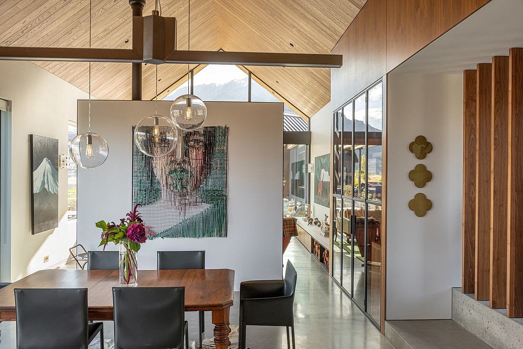 Warm modern interior with wooden beams, pendant lights, and glass walls overlooking mountains.