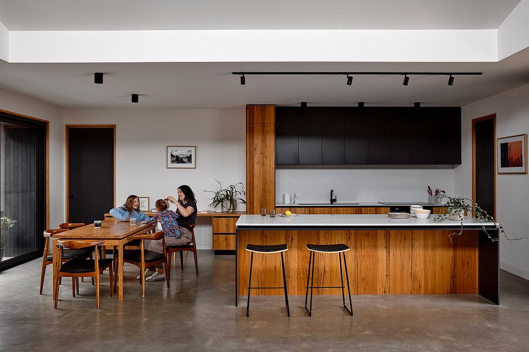 A modern, open-plan kitchen and dining area with wood accents and sleek black cabinetry.