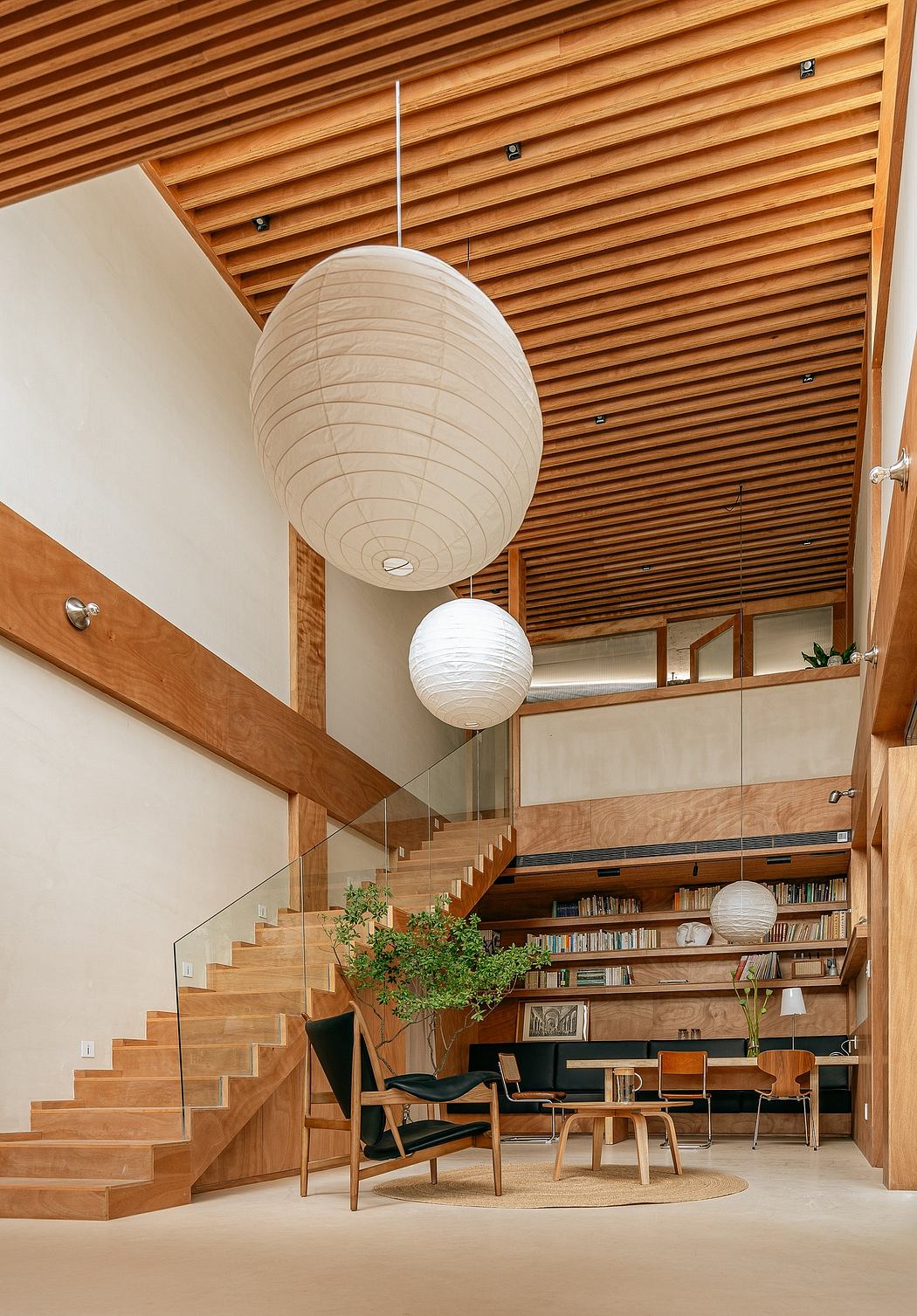 Minimalist interior with wooden slat ceiling, paper lanterns, and built-in bookshelves.