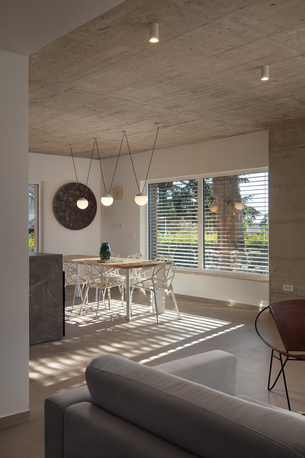 A modern dining area with concrete ceiling, pendant lights, and views to the outdoors.