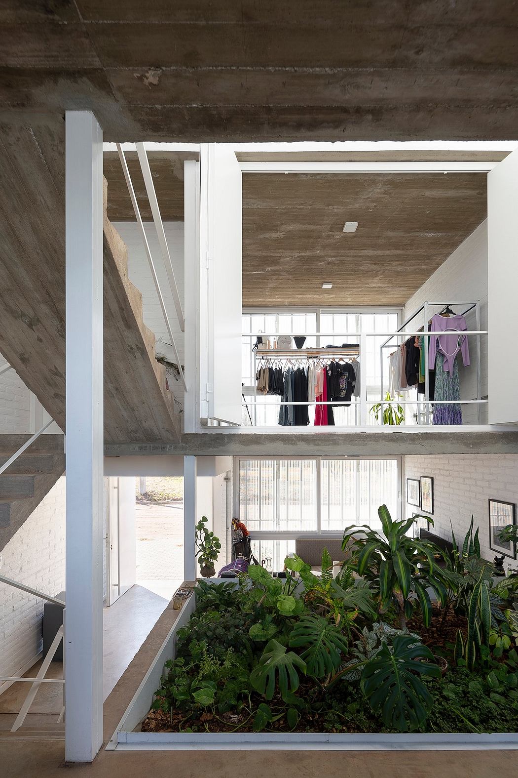 A modern industrial loft with a large indoor garden, exposed concrete, and an open closet space.