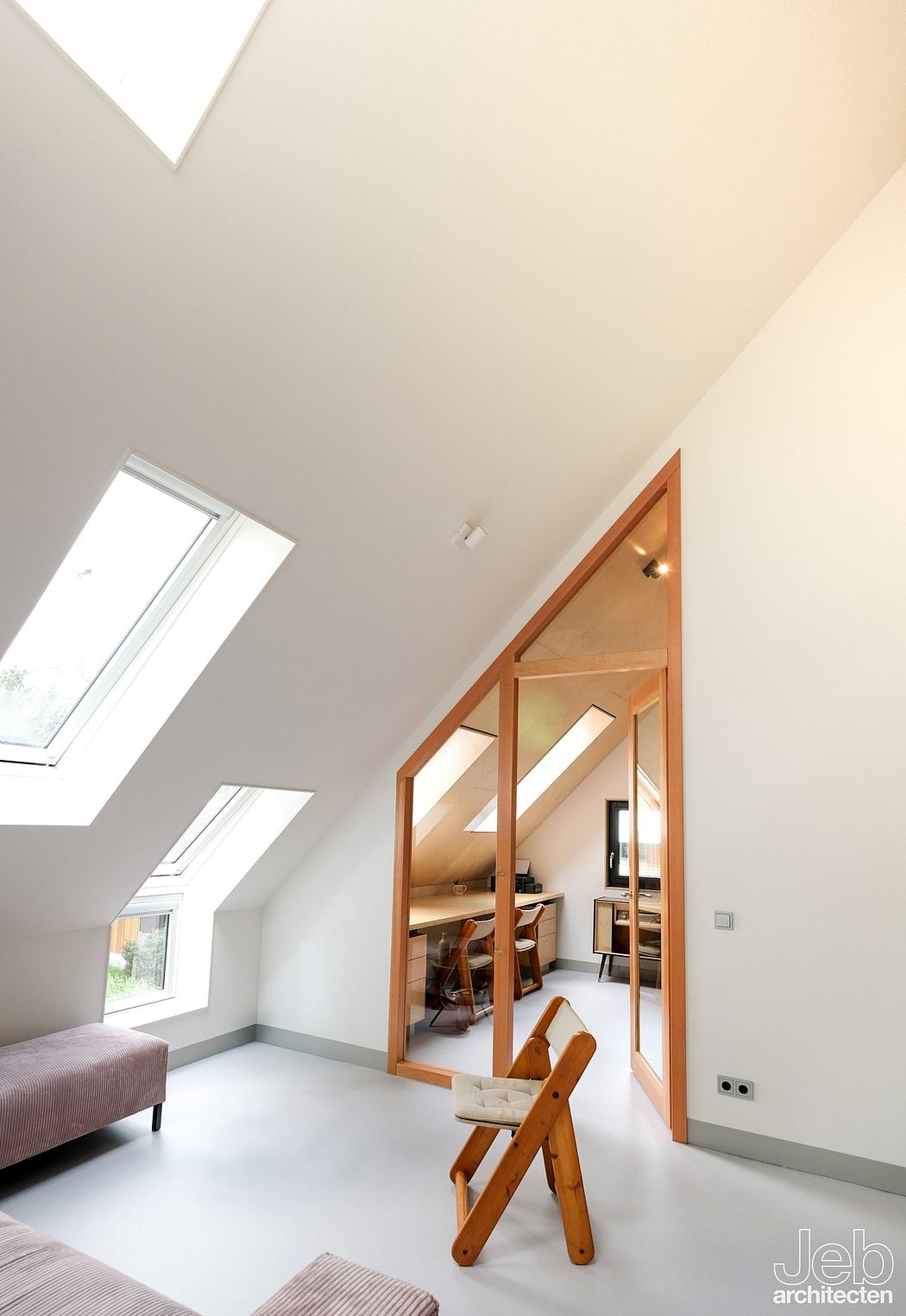 Bright, modern attic space with wooden framing, skylights, and integrated office area.