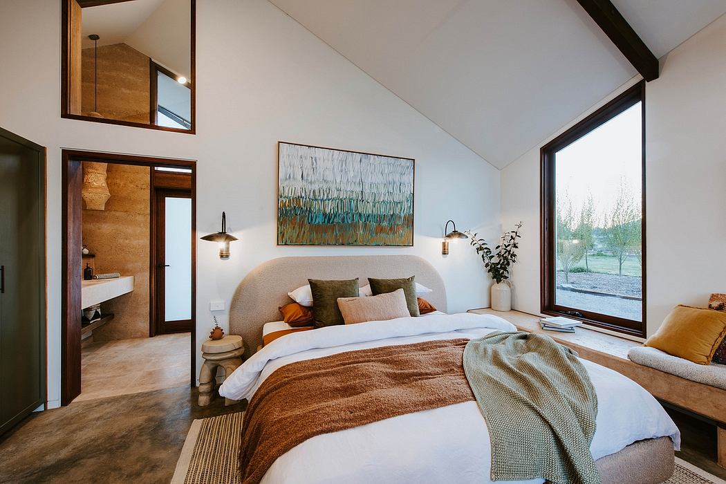 Spacious bedroom with vaulted ceiling, large windows, rustic wood accents, and artistic wall decor.