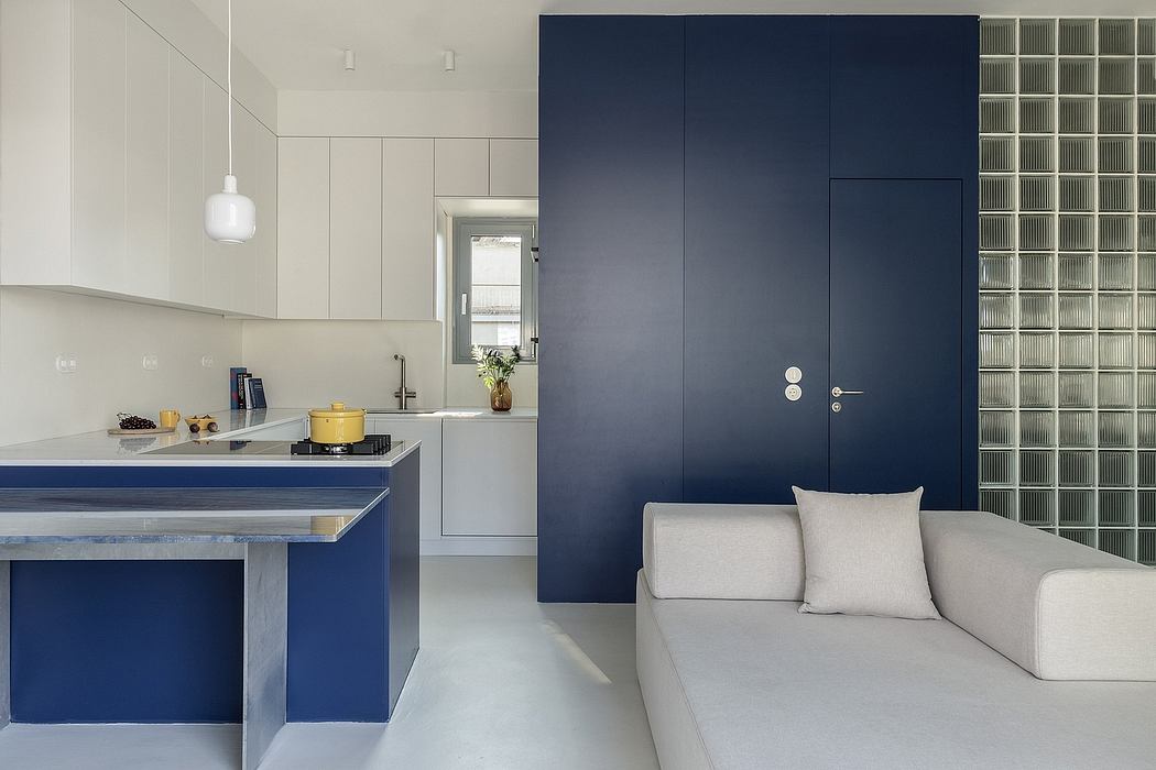 A modern, open-plan kitchen and living space with blue accents, white built-ins, and minimal decor.