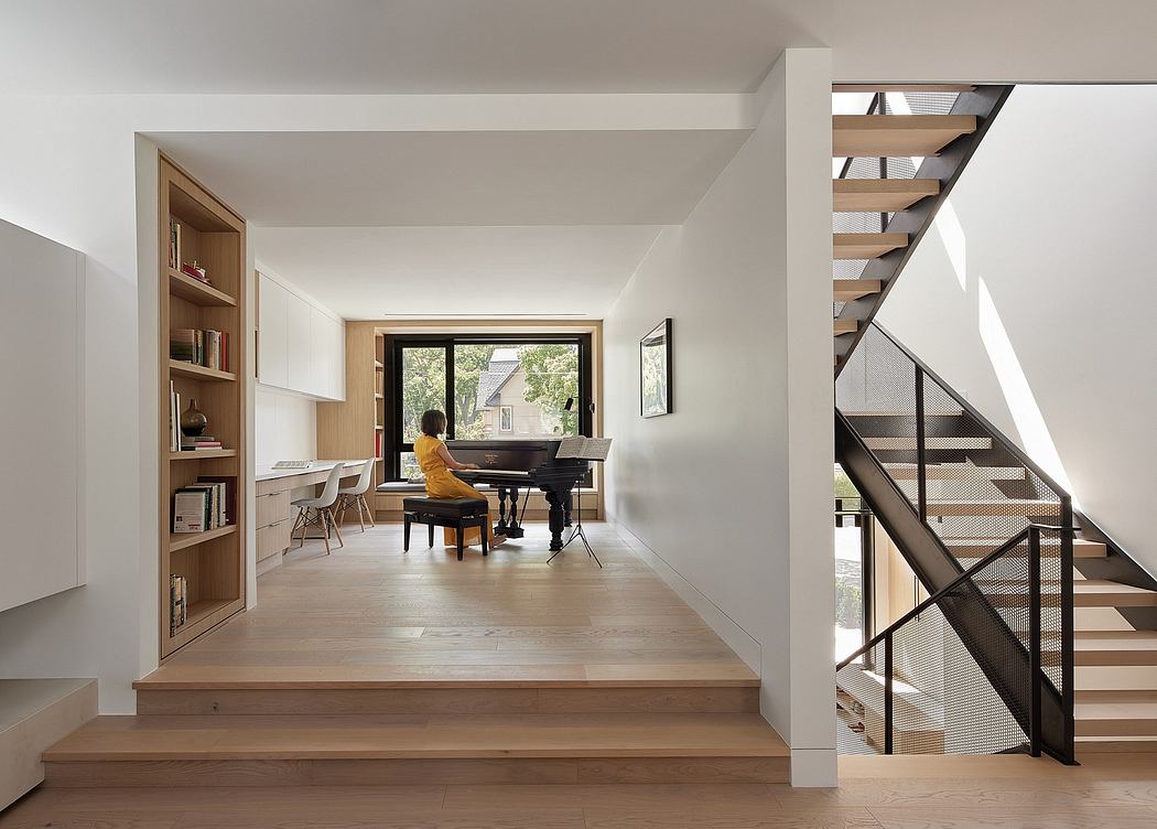 Bright, modern living space with wooden stairs, piano, and built-in shelving.