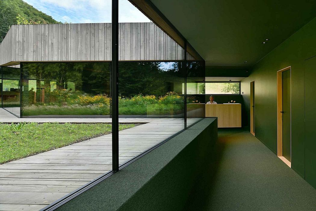 Sleek, modern interior with expansive windows overlooking verdant landscape.