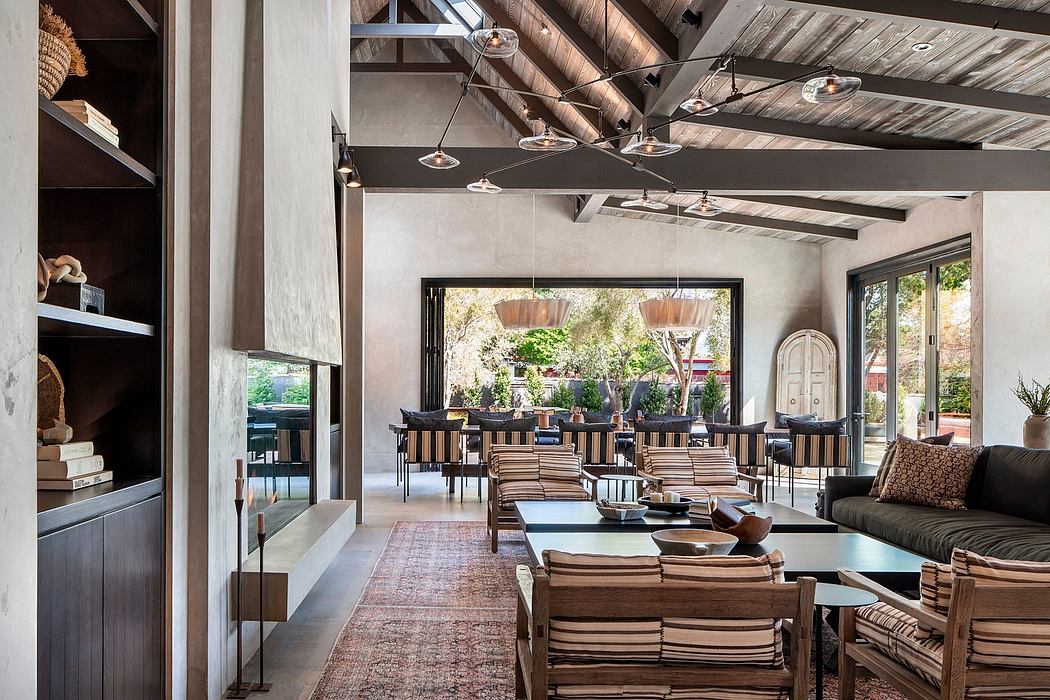 Rustic, open-concept space with exposed beams, modern furnishings, and lush outdoor views.