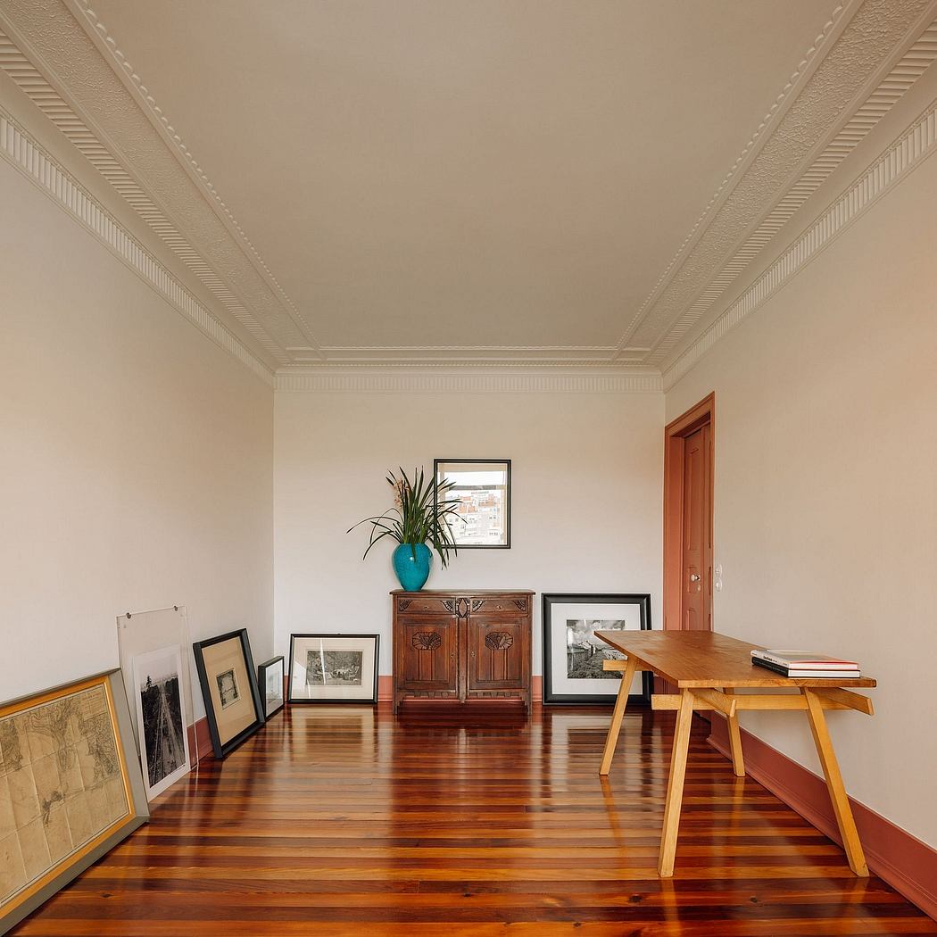Elegant room with ornate ceiling moldings, hardwood floors, and a wooden cabinet displaying artwork.