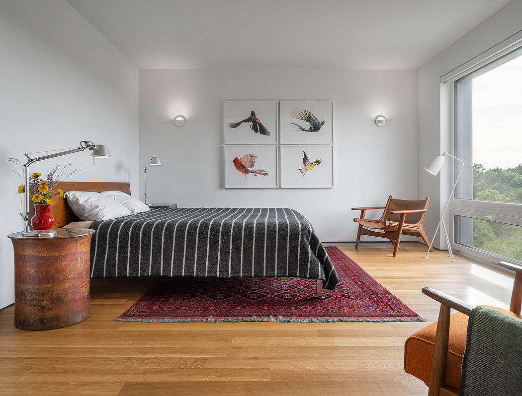 Minimalist bedroom design with striped bedding, vintage Persian rug, and bird artwork.