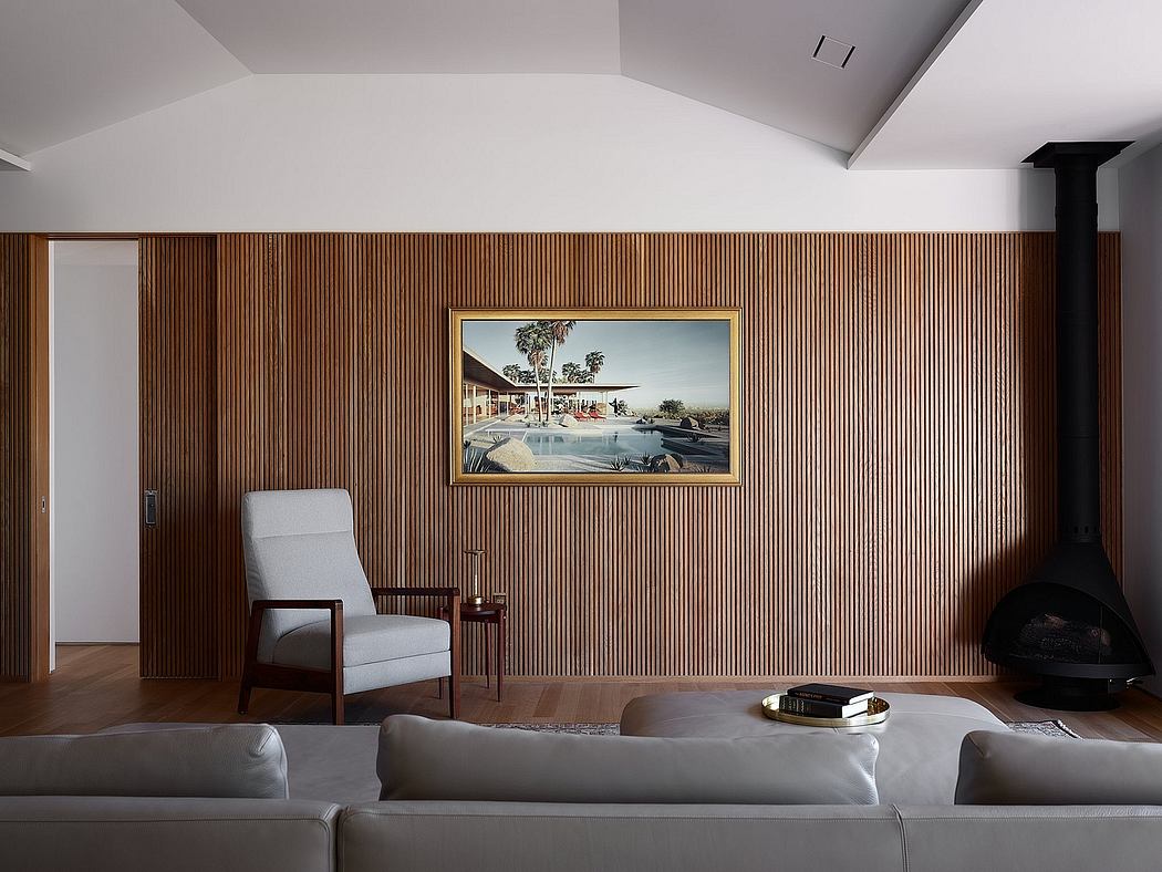 Minimalist living room with wood paneled walls, modern gray furniture, and a large framed artwork.