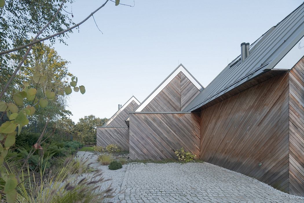 Striking angular architecture with wood and steel elements, leading to a garden path.