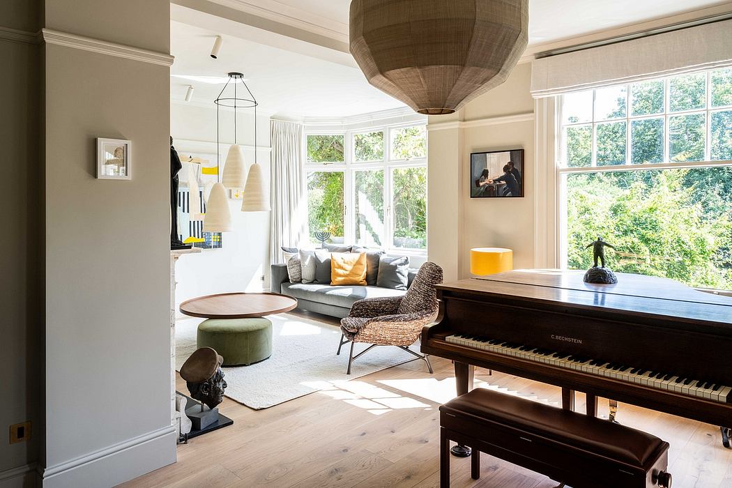 Spacious living room with a grand piano, cozy seating area, and large windows overlooking greenery.