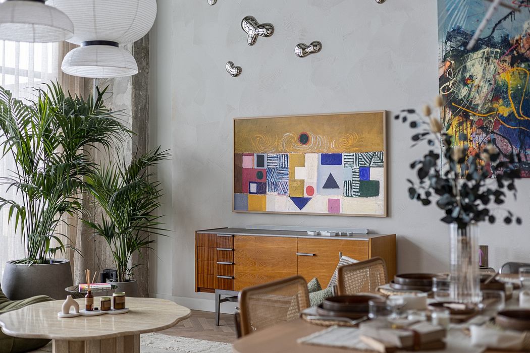 Modern eclectic living room with mid-century credenza, abstract artwork, and lush greenery.