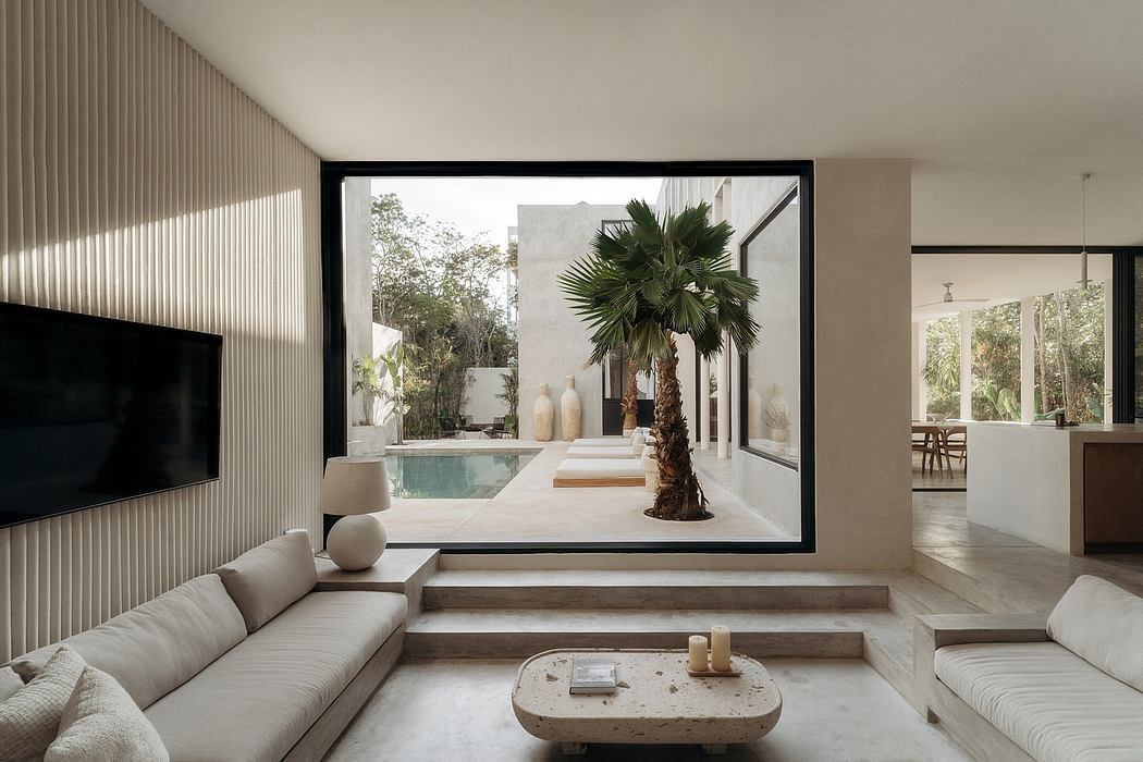 Minimalist living room with floor-to-ceiling windows, patio, and lush palm tree.