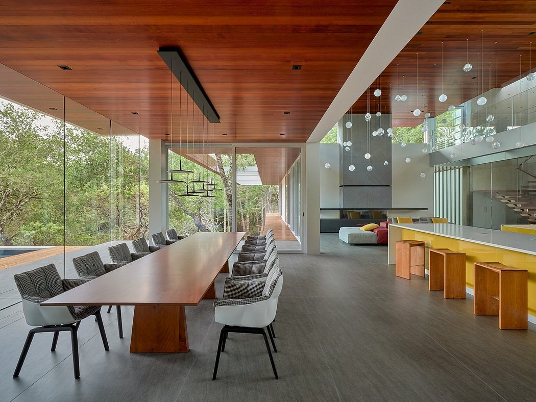 A modern, open-concept interior with wood accents, hanging light fixtures, and a large dining table.