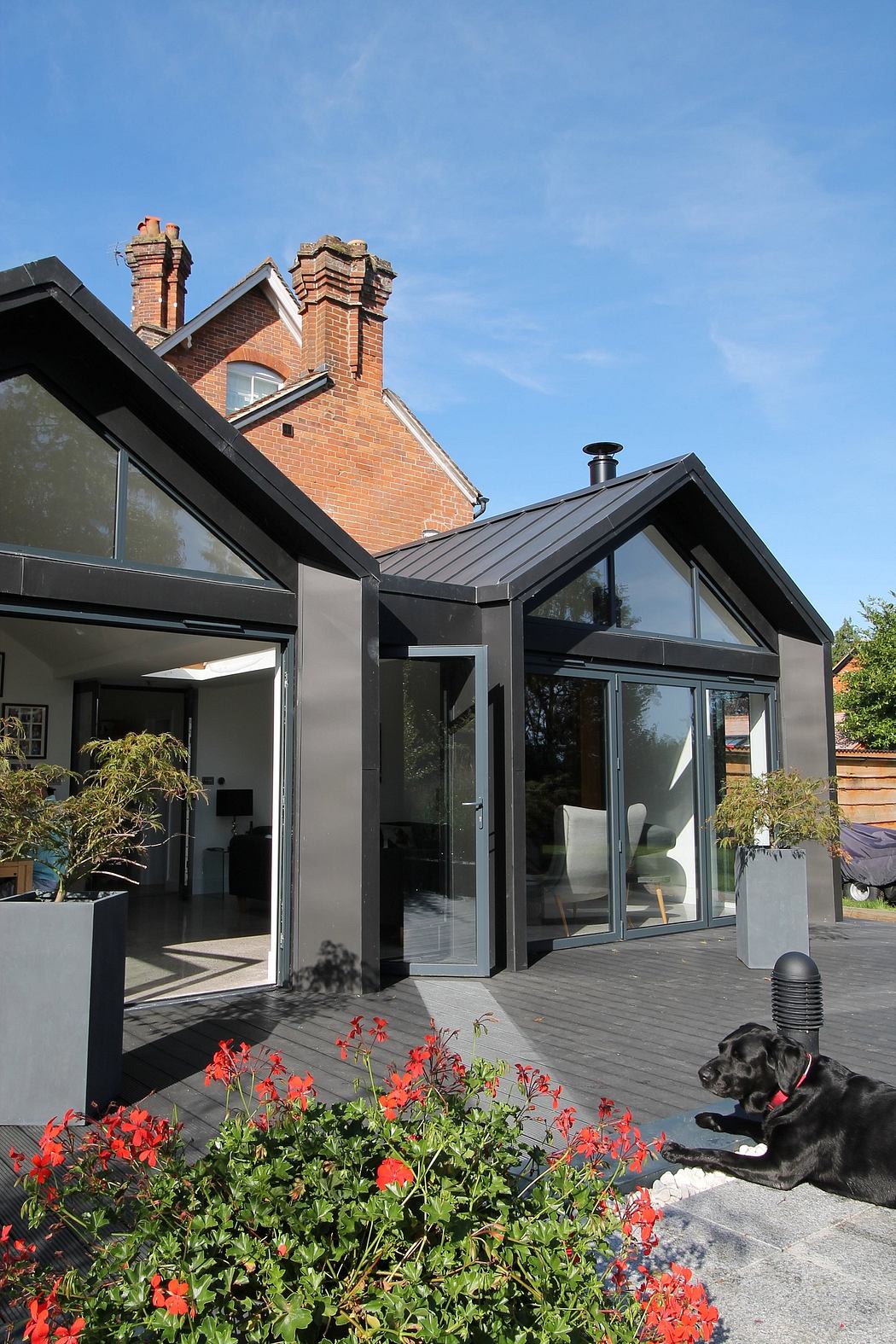 A modern glass-walled extension with a brick chimney stack complements the traditional house.