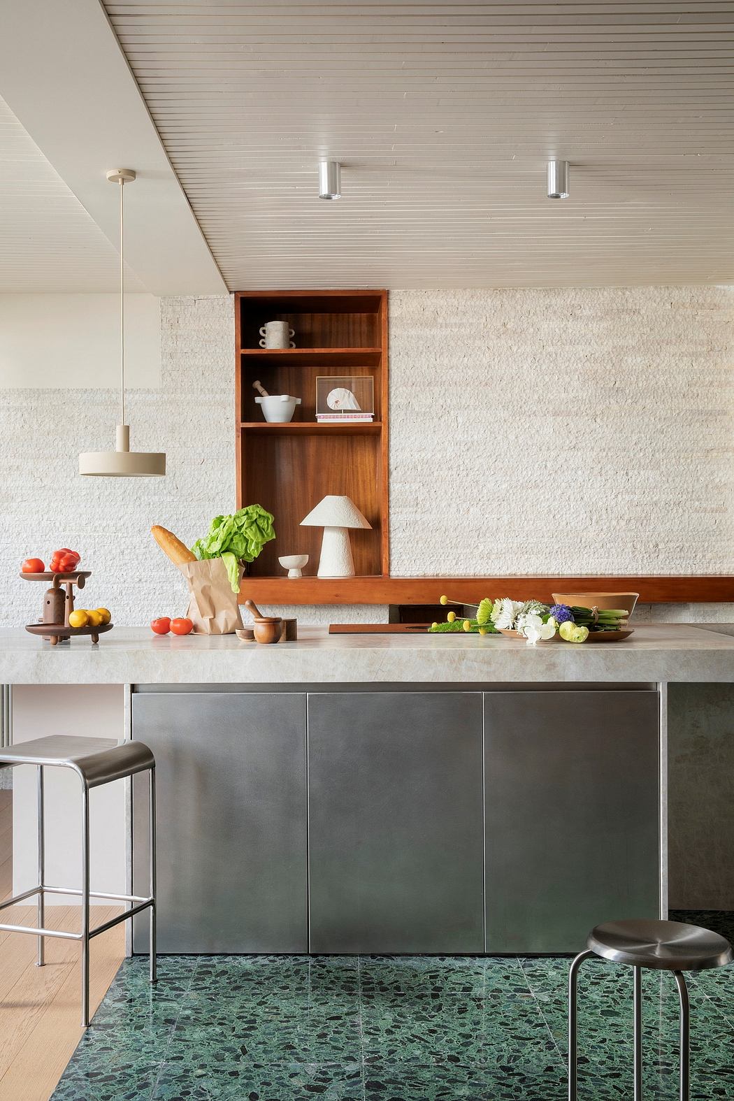 A modern kitchen with a wooden shelving unit, concrete walls, and a green terrazzo floor.