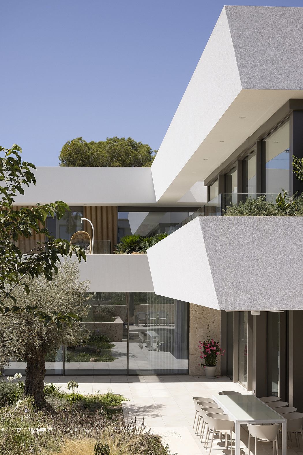 Modern minimalist architectural design with geometric shapes, glass walls, and lush landscaping.