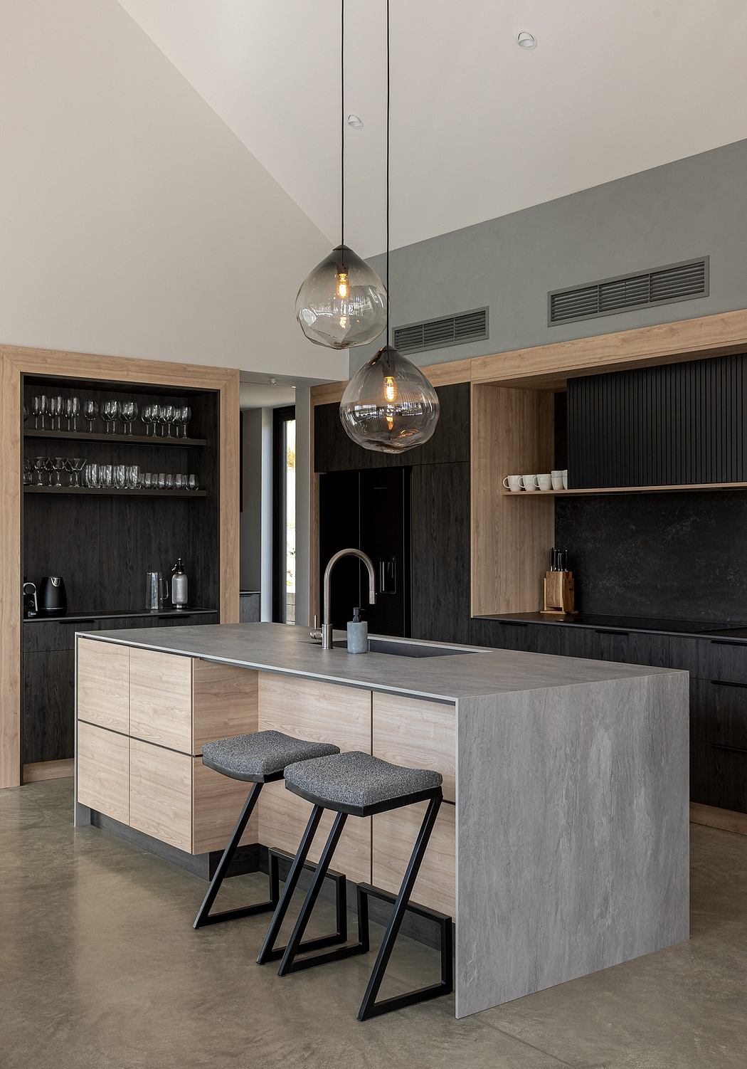 Modern kitchen with sleek gray countertop, pendant lights, and black cabinetry.