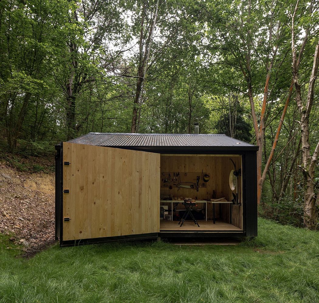 Rustic wooden shed with a metal roof, surrounded by lush greenery and trees.