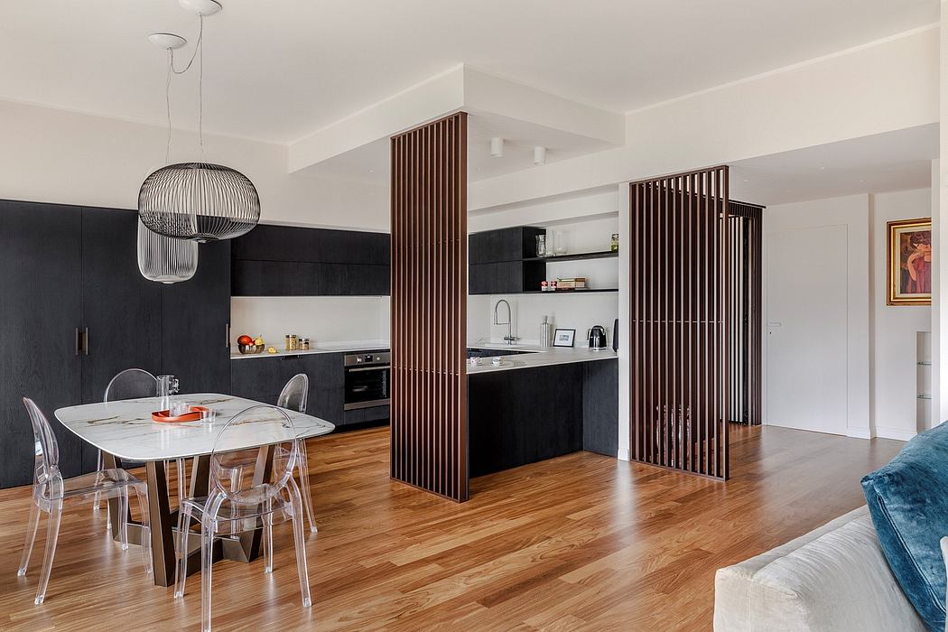 Modern open-plan kitchen with black cabinetry, wooden partitions, and glass dining table.