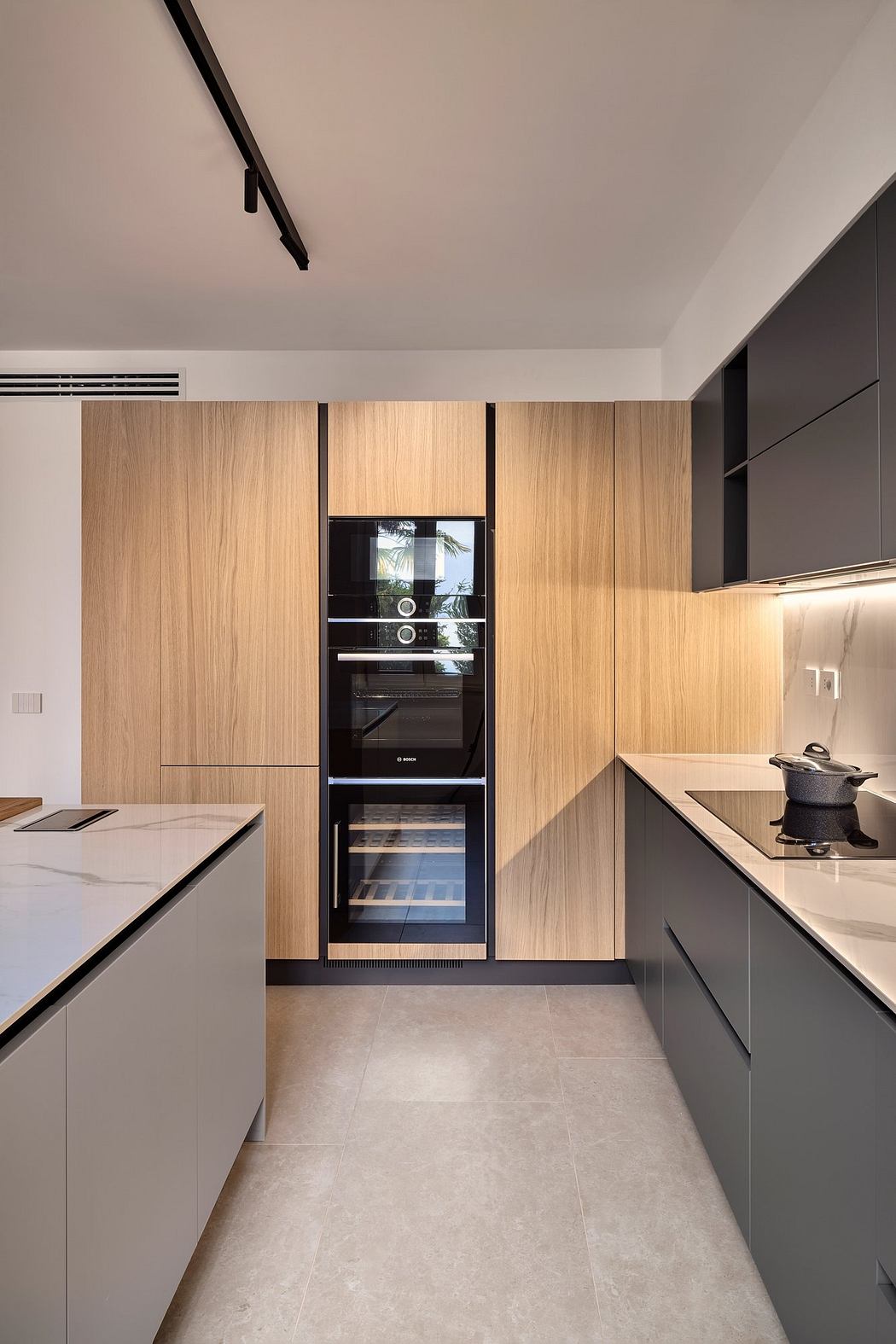 Modern, minimalist kitchen with sleek wood and black cabinetry, integrated appliances, and track lighting.
