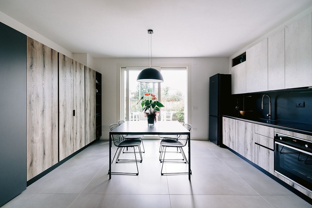 Modern kitchen and dining area with wooden accent walls, black fixtures, and a potted plant.