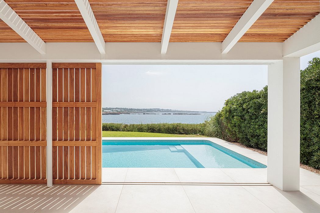 Spacious modern patio with wood-paneled ceiling, sliding doors, and infinity pool with scenic view.