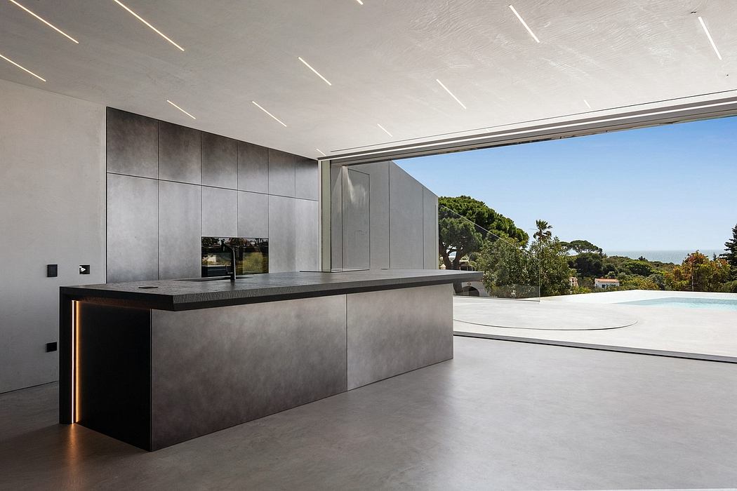 Sleek, modern kitchen with minimalist countertops and glass walls overlooking outdoor pool.