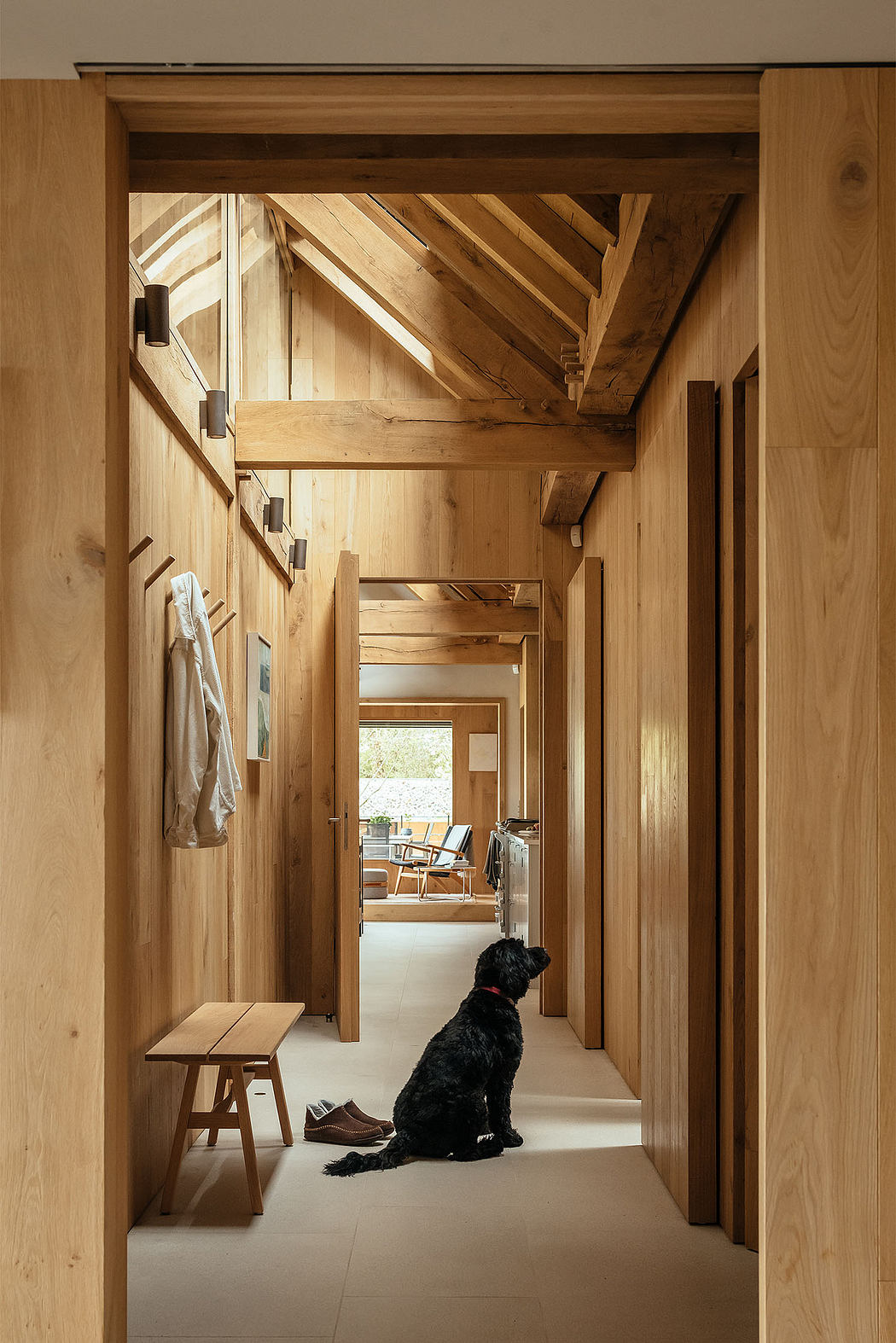 Warm-toned wooden interior with exposed beams and a dog sitting in the hallway.