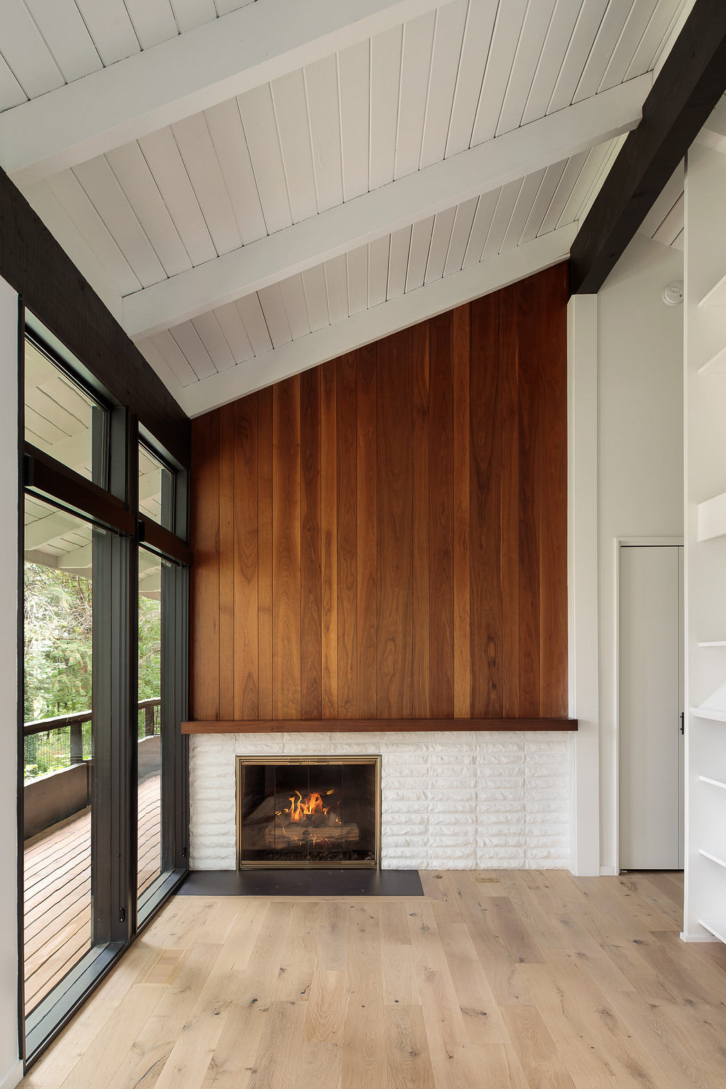 A modern, rustic interior with a wooden accent wall, a white brick fireplace, and hardwood floors.