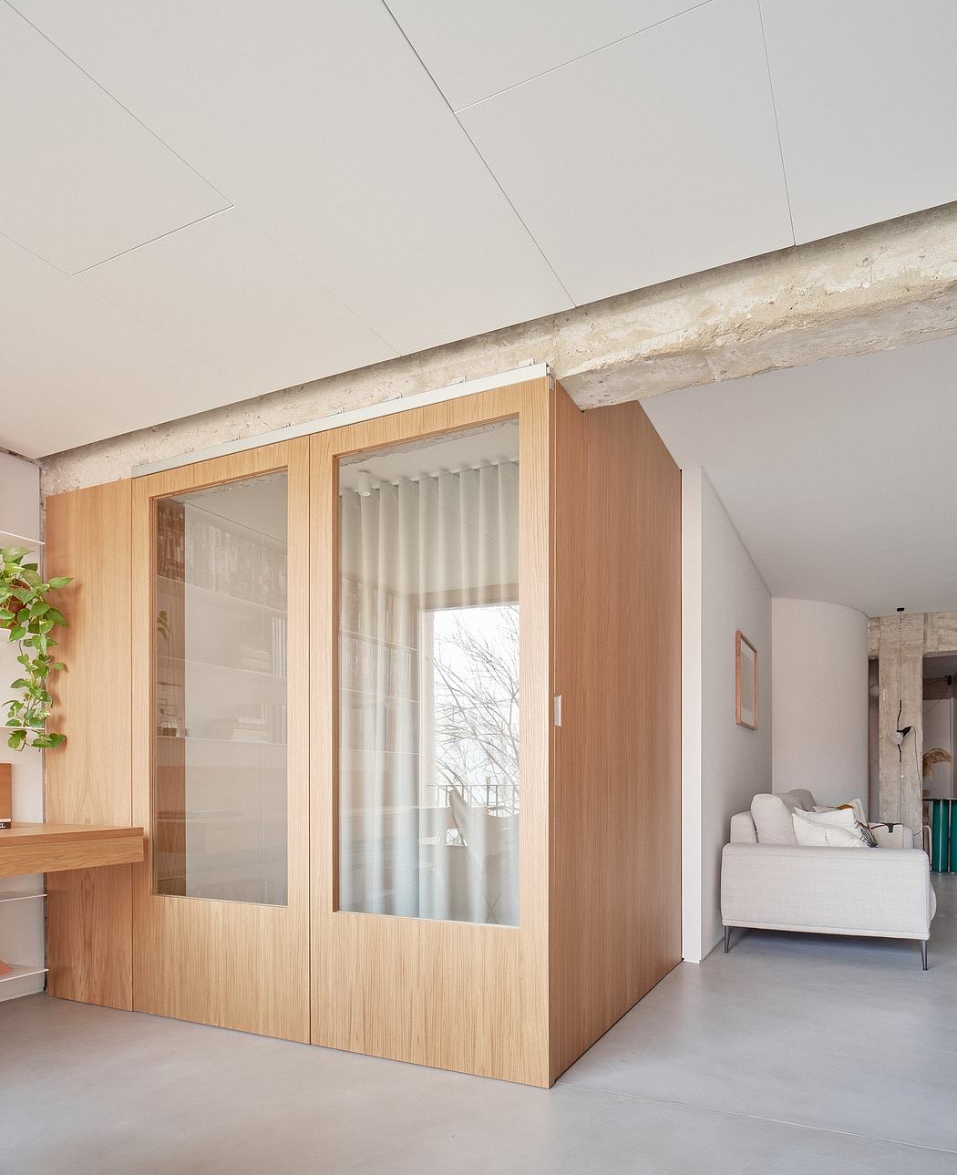 A minimalist, wooden partition with glass panels divides the room, creating a cozy nook.