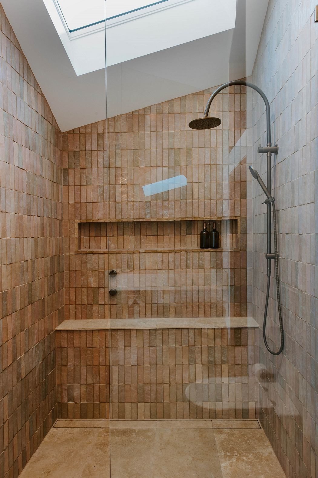 A spacious walk-in shower with tiled walls, built-in shelves, and a sleek showerhead.