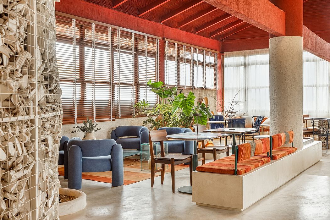 A modern, rustic lounge area with wooden beams, stone walls, and vibrant orange seating.