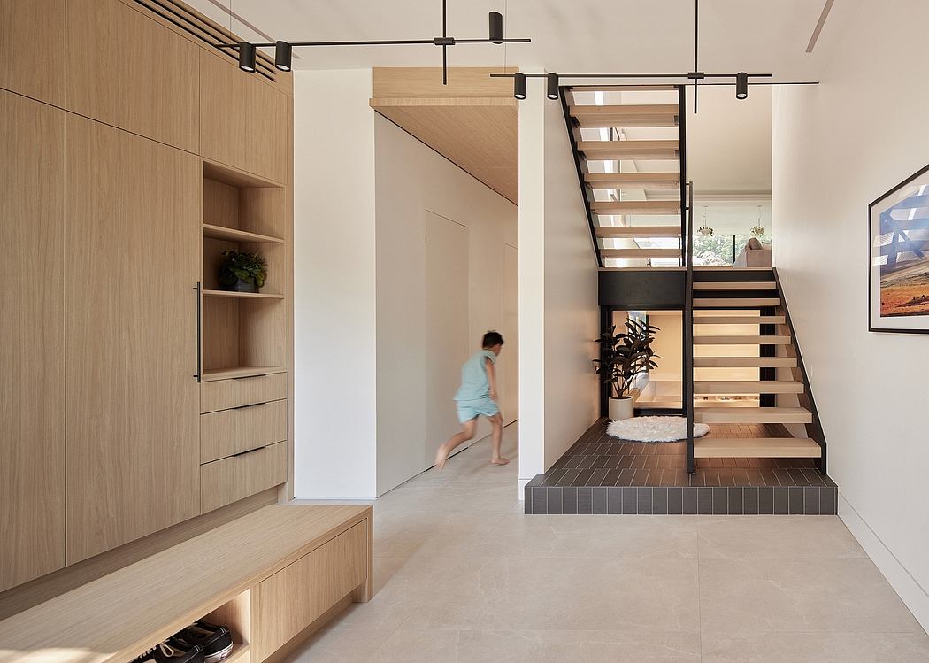 Modern entryway with wooden cabinetry, floating stairs, and minimalist lighting fixtures.