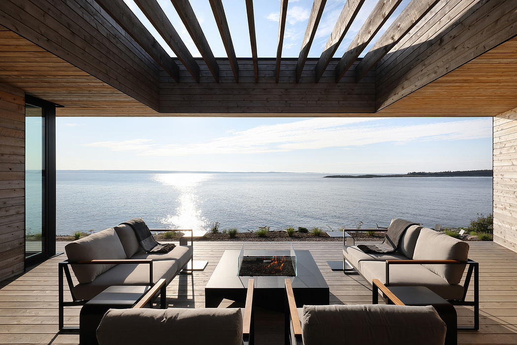 Striking modern cabin with large windows framing stunning ocean view and outdoor seating.