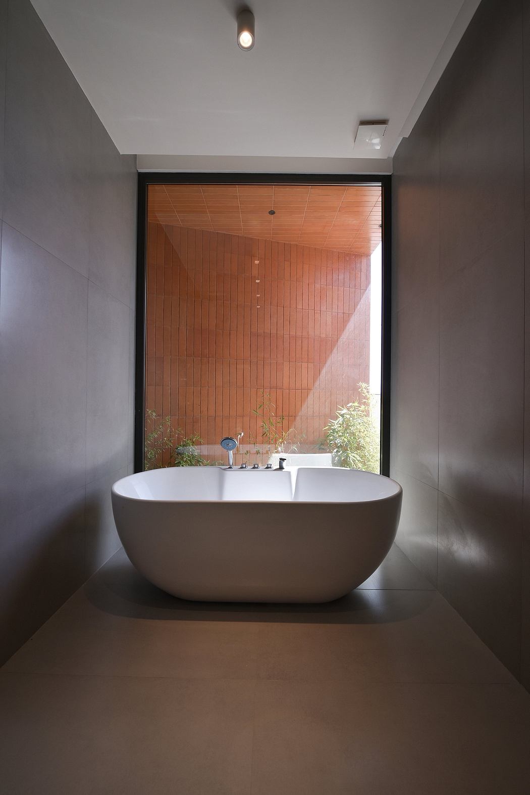 A modern bathroom with a freestanding bathtub, wood paneled walls, and natural light.