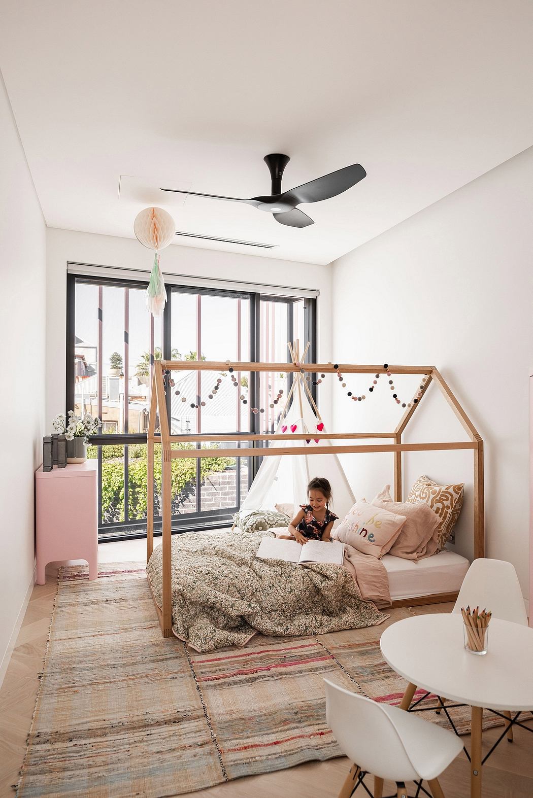 A cozy bedroom with a wooden frame bed, colorful textiles, and a modern ceiling fan.