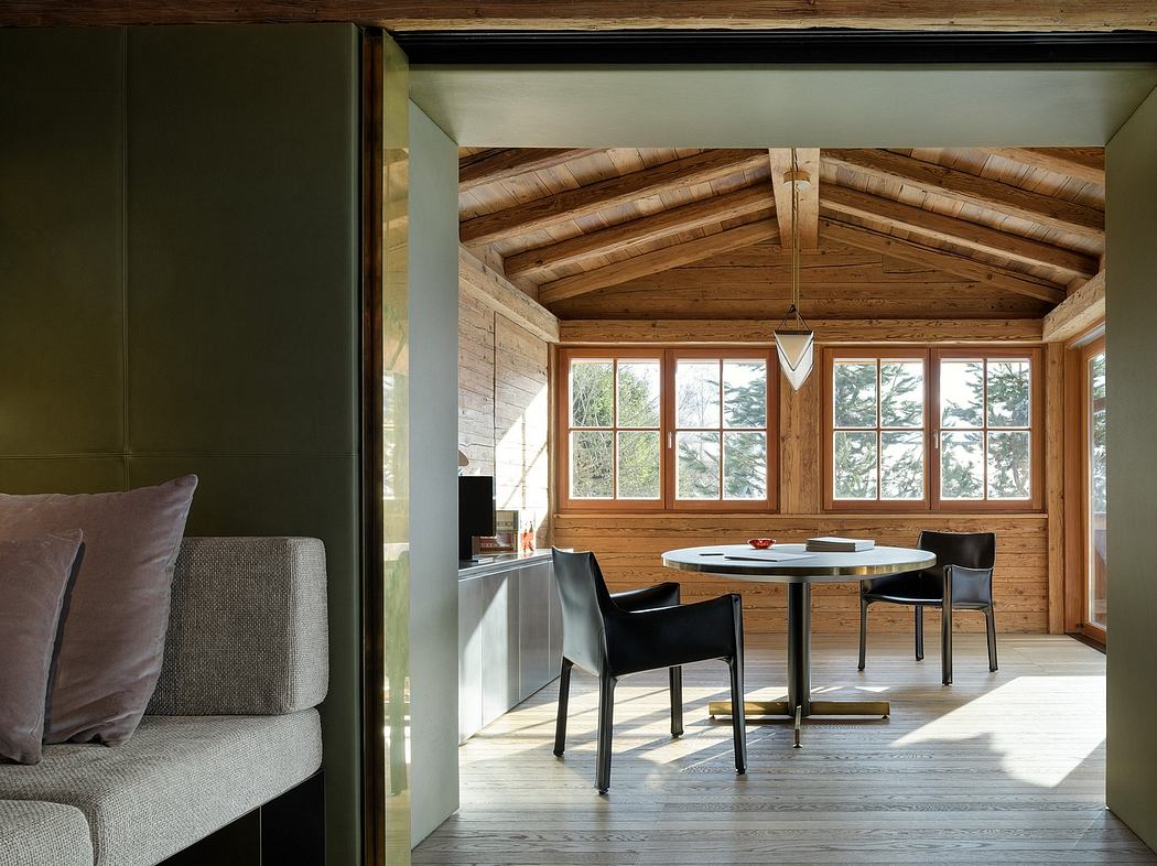 Rustic chalet-style interior with wooden beams, large windows, and modern furnishings.