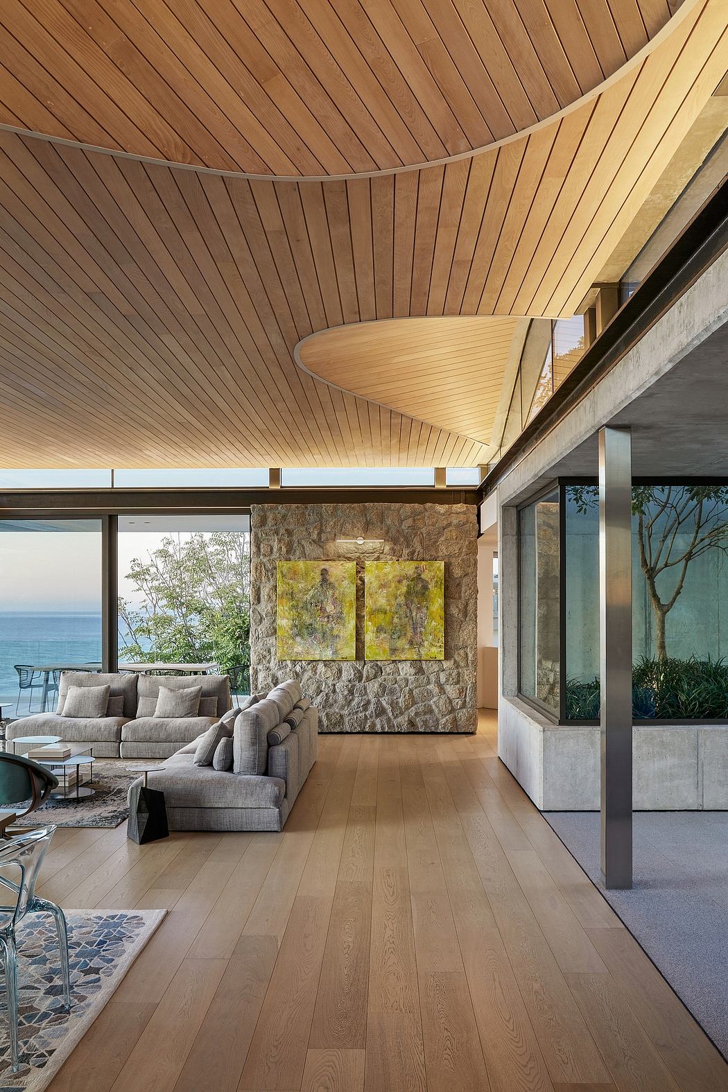 Stunning modern interior with curved wooden ceiling, stone accent wall, and panoramic ocean view.